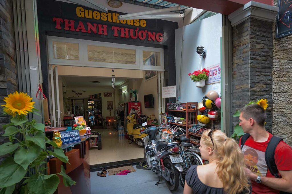 Westerse reizigers bij de ingang van een lokaal Vietnamese guesthouse, overnachten in lokale accommodaties is een van de manieren om verantwoord te reizen en de lokale economie in Vietnam te steunen
