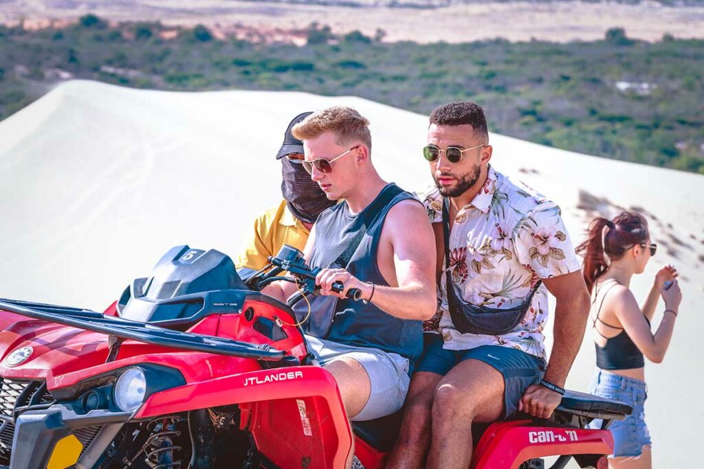Toeristen op een rode quad op de witte zandduinen van Mui Ne — quadrijden is een van de populairste activiteiten bij een bezoek aan de duinen