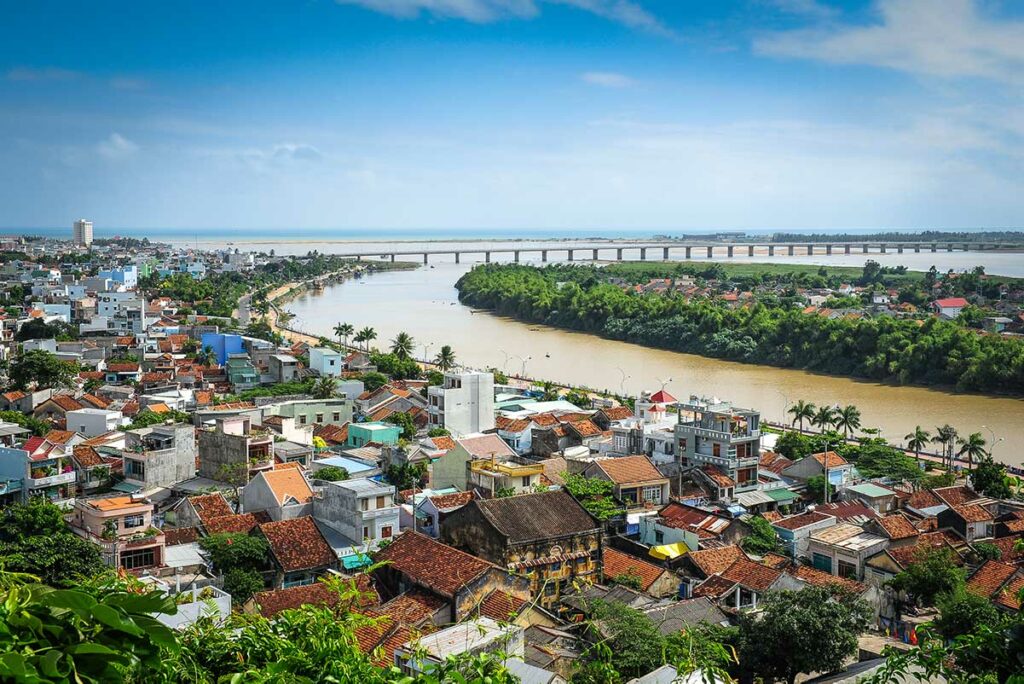 Uitzicht over de stad Tuy Hoa in Phu Yen met kleurrijke huizen, een brede rivier met een lange brug en de zee zichtbaar in de verte — de hoofdstad van Phu Yen is een rustige kuststad langs de nationale route