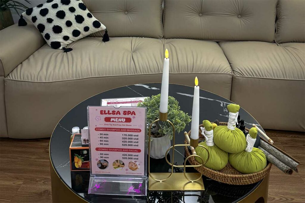 Massagemenu van Ellsa Spa in Vietnam op een salontafel met prijzen in Vietnamese dong voor shampoo en massage combinaties