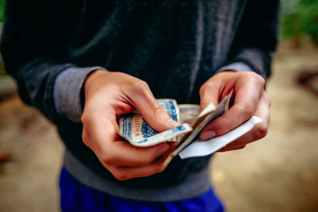 Handen tellen Vietnamese dong biljetten, contant betalen blijft in Vietnam de meest gebruikte betaalmethode ook voor Wise-gebruikers die geld hebben opgenomen