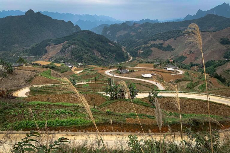 Slingerende weg over de Na Tenh pas langs akkers en boerderijen tussen de bergen van Cao Bang