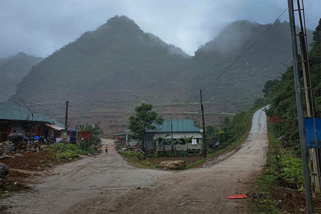 Mistige ochtend in het dorp Lung Pan in Cao Bang, met een steile betonweg richting de bergen