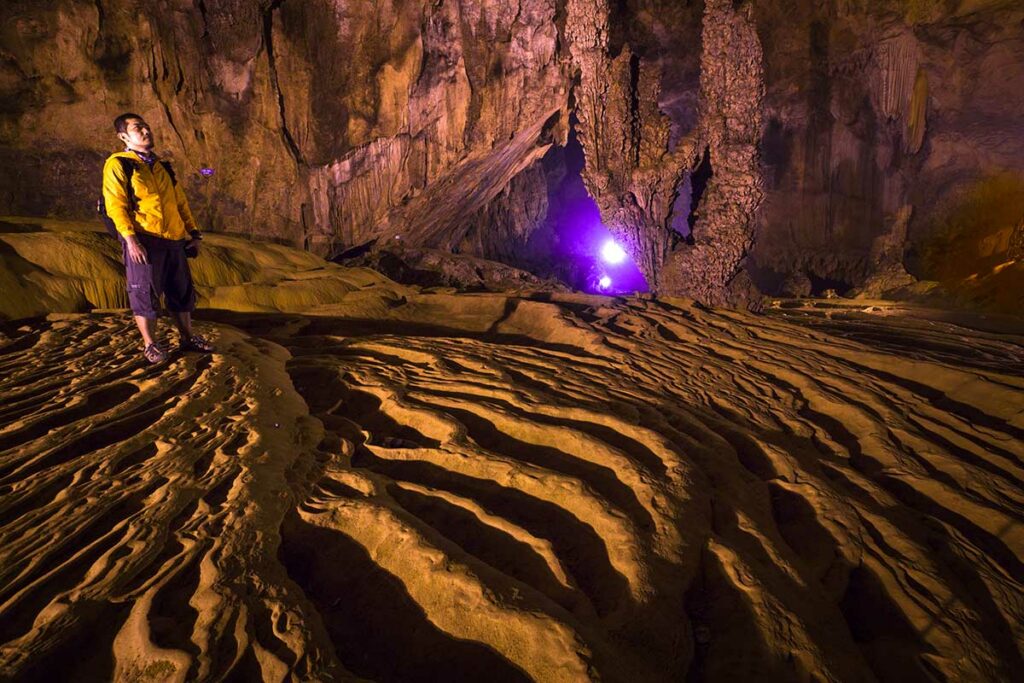 Man kijkt omhoog naar de kalksteenformaties en gegolfde bodem in de Nguom Ngao grot, Cao Bang