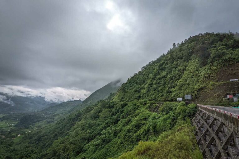Bergweg langs een beboste helling bij Nguyen Binh, met wolken die laag over de vallei hangen