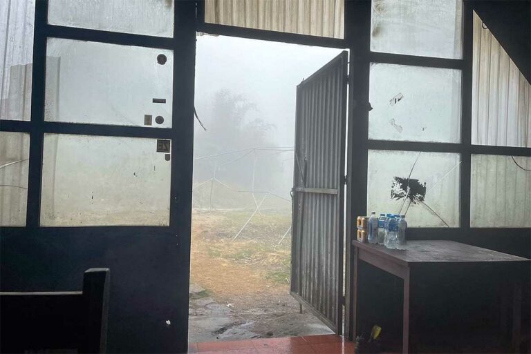 Blik door de open deur van een kampgebouw op de Fansipan, met dichte mist buiten.