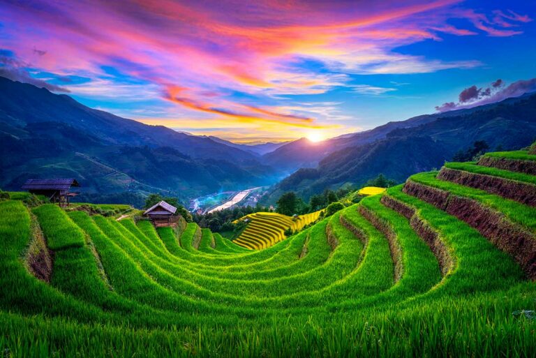 Groene rijstterrassen in hoefijzervorm bij zonsondergang met houten veldhuisjes en bergen in Mu Cang Chai