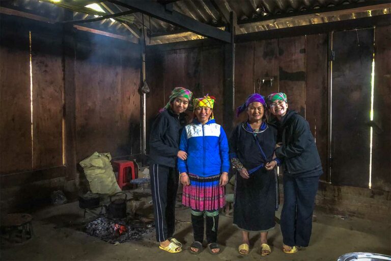 Vier vrouwen bij het open kookvuur in een houten homestay in Mu Cang Chai, Yen Bai