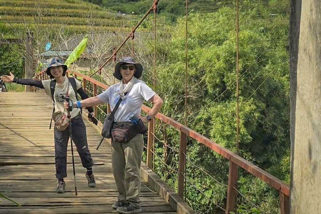 Twee wandelaars op een houten brug onderweg door de bergen bij Mu Cang Chai, Yen Bai