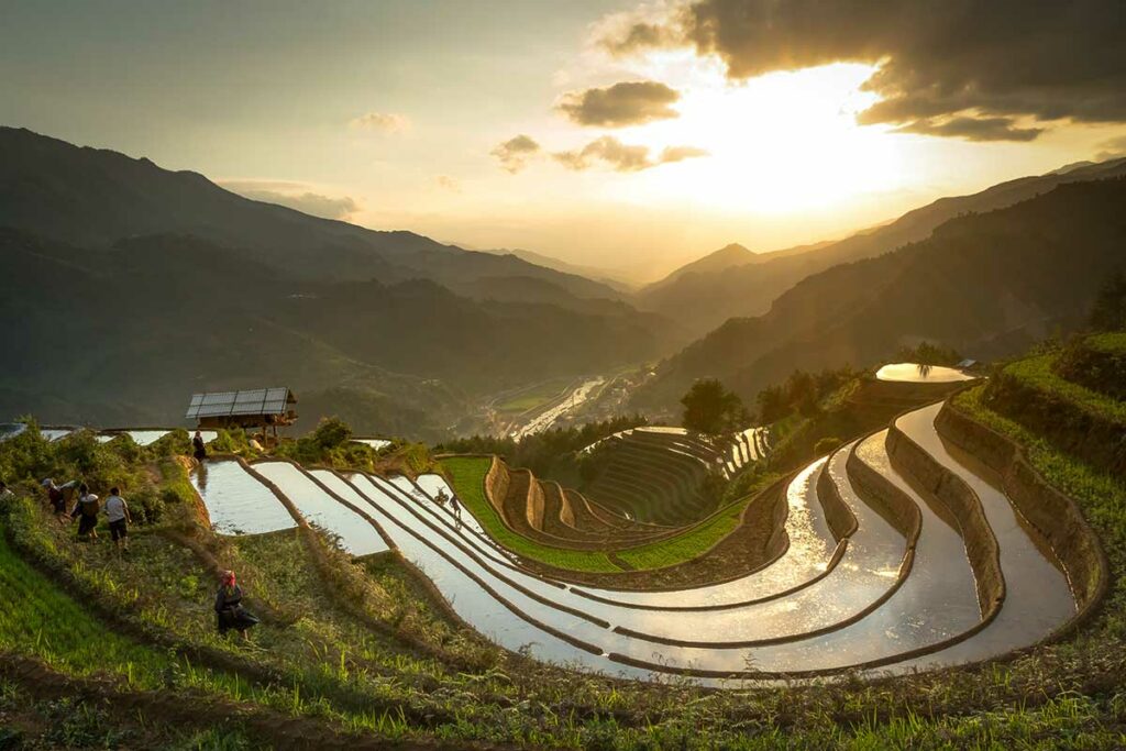 Ondergelopen rijstterrassen bij zonsondergang met boeren op het land in Sang Nhu, Mu Cang Chai