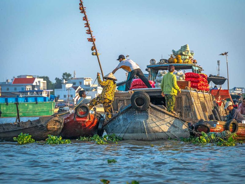 Handelaren die goederen overladen tussen boten op de Cai Rang drijvende markt bij Can Tho, een van de grootste en meest levendige markten in de Mekong Delta