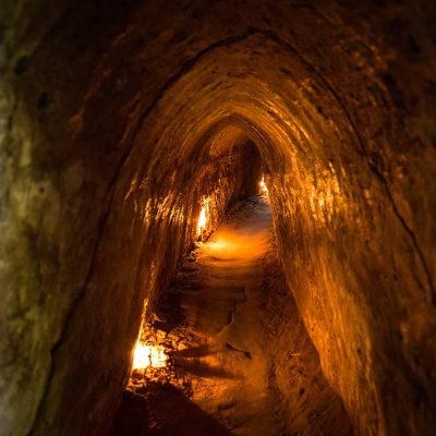 Smalle ondergrondse tunnelgang van het Cu Chi Tunnels netwerk, verlicht om bezoekers een beeld te geven van het leven onder de grond