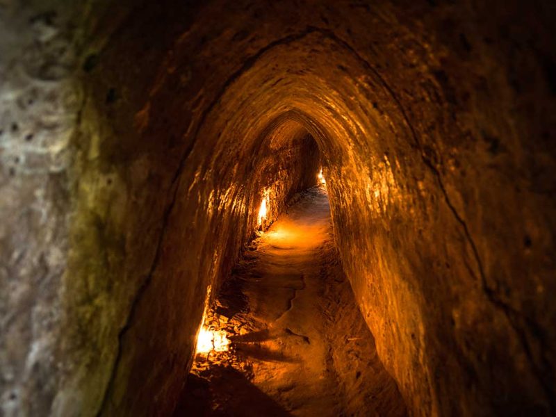 Smalle ondergrondse tunnelgang van het Cu Chi Tunnels netwerk, verlicht om bezoekers een beeld te geven van het leven onder de grond