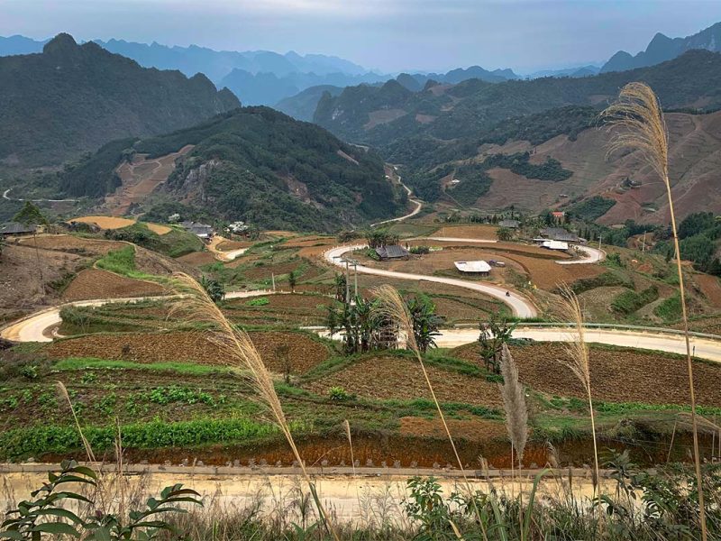 Slingerende weg over de Na Tenh pas langs akkers en boerderijen tussen de bergen van Cao Bang