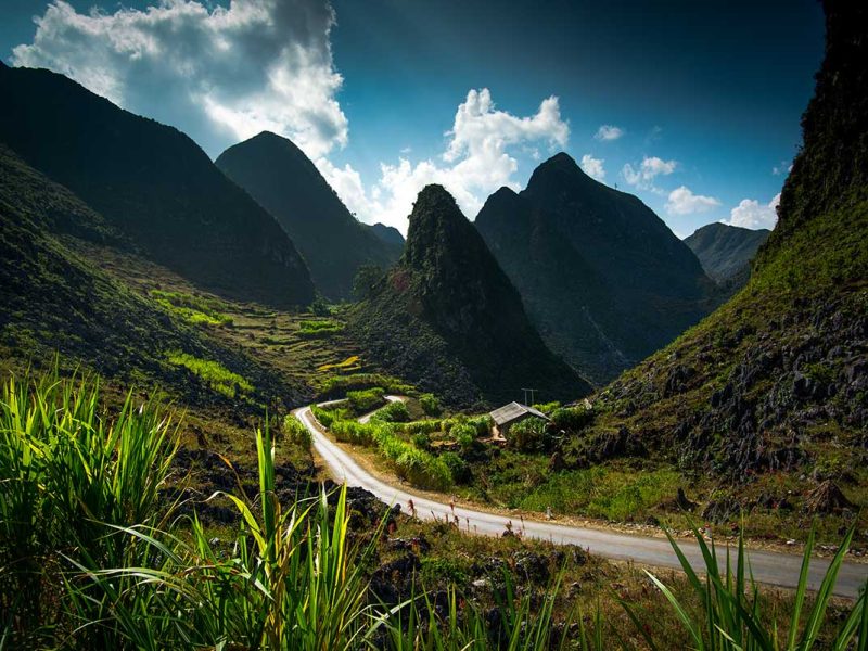 Kronkelende weg door het iconische karstlandschap van de Ha Giang Loop, omringd door steile bergen en groene valleien.
