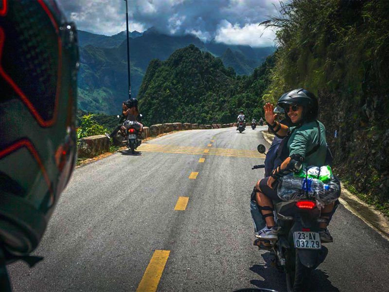 Reizigers op een Easy Rider motorbiketocht langs de Ha Giang Loop, rijdend door hoge bergpassen met panoramisch uitzicht.