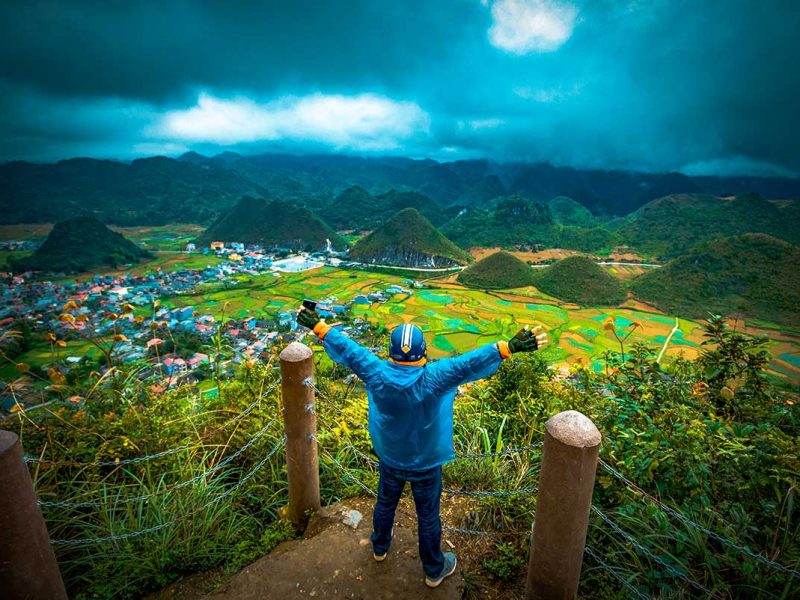 Reiziger op viewpoint boven de Quan Ba Twin Mountains met uitzicht over rijstvelden en valleien.