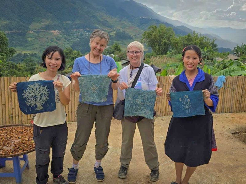 Vier vrouwen tonen zelfgemaakte indigo geverfde doeken met witte patronen in Mu Cang Chai, Yen Bai