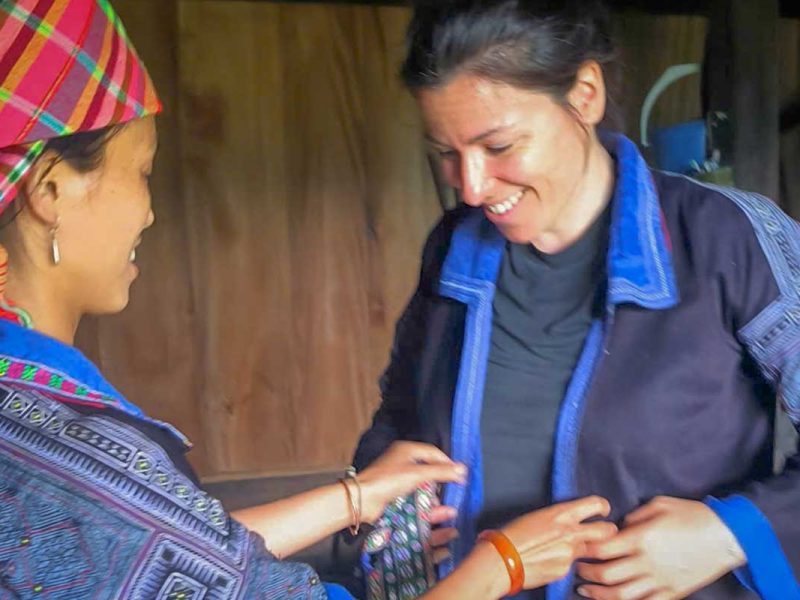 Lokale vrouw helpt een reiziger met het aantrekken van traditionele kleding in een woning in Mu Cang Chai