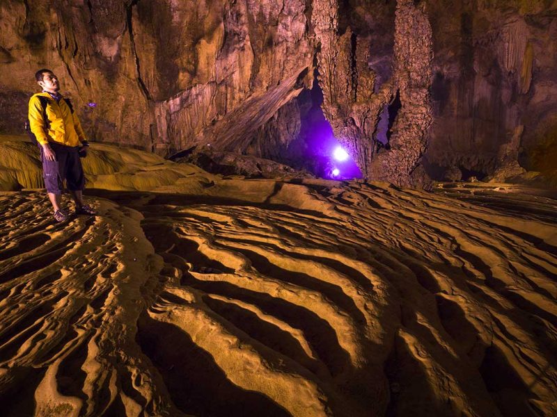 Man kijkt omhoog naar de kalksteenformaties en gegolfde bodem in de Nguom Ngao grot, Cao Bang