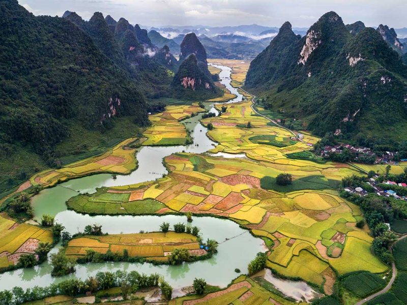 Luchtfoto van Phong Nam Valley met rivier, dorpen en uitgestrekte rijstvelden tussen kalkstenen bergen in Cao Bang