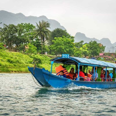 Boot met bezoekers op de Son-rivier bij Phong Nha, onderdeel van de boottocht richting Phong Nha Cave door het landelijke landschap.