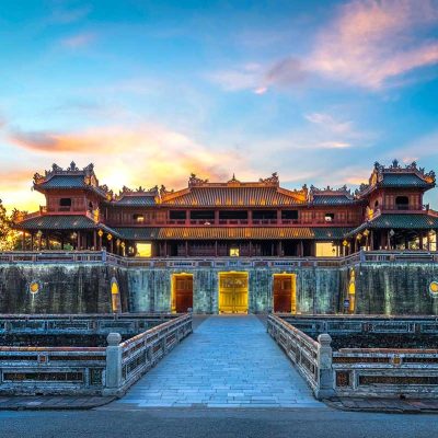 Monumentale toegangspoort van de Imperial City of Hue, het keizerlijke hart van de Nguyen-dynastie, gezien bij zonsondergang met symmetrische brug en stadsmuren.