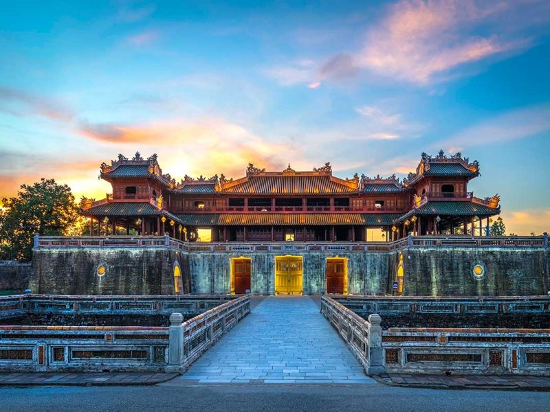 Monumentale toegangspoort van de Imperial City of Hue, het keizerlijke hart van de Nguyen-dynastie, gezien bij zonsondergang met symmetrische brug en stadsmuren.