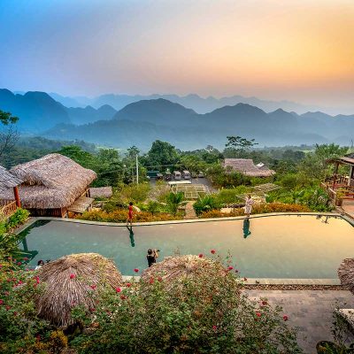 Uitzicht vanaf Pu Luong Eco Garden over de groene vallei en bergketens, met traditionele bungalows en rijstvelden in de omgeving
