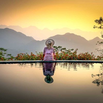 Zonsondergang bij Pu Luong Eco Garden met silhouetten van bergen, bloemen en een infinity pool die het landschap weerspiegelt