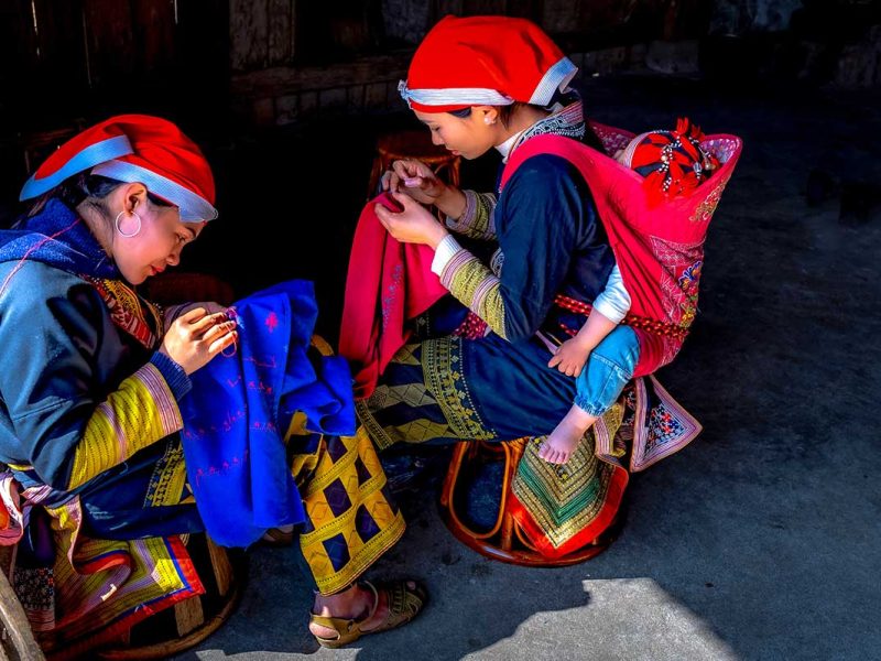 Red Dao vrouwen werken aan traditioneel borduurwerk in Sapa, een intiem moment voor portret- en culturele fotografie in Noord-Vietnam.
