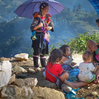 Etnische vrouwen en kinderen uit de regio Sapa rusten langs een bergpad, een intiem moment voor documentaire en portretfotografie in Noord-Vietnam.