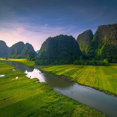 Rijstvelden van Tam Coc in Ninh Binh gezien vanuit de lucht, met rivier, kalkstenen bergen en groene landbouwgronden in het karstlandschap