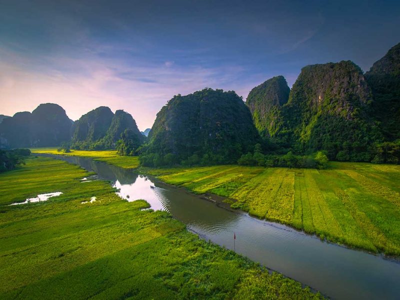 Rijstvelden van Tam Coc in Ninh Binh gezien vanuit de lucht, met rivier, kalkstenen bergen en groene landbouwgronden in het karstlandschap