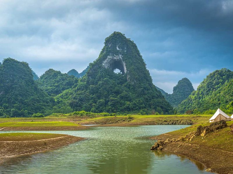 Kampeerplek bij Angel Eye Mountain met tenten langs het water, omringd door karstbergen en stilte in het landschap van Cao Bang.
