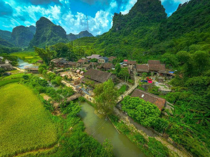 Luchtfoto van Khuoi Ky met stenen huizen langs een riviertje en rijpe rijstvelden in Cao Bang