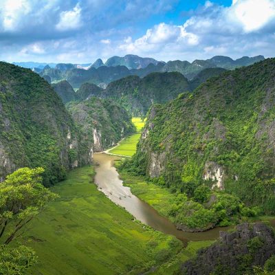 Panoramisch uitzicht vanaf Mua Cave in Ninh Binh, met kronkelende rivier, rijstvelden en steile kalksteenbergen in het Tam Coc landschap